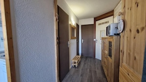 A narrow hallway with wooden cabinets, a small wooden bench, and a microwave on a cabinet. - 100m from ski slopes, 1st floor, swimming pool, balcony, tv, 31m², Les Arcs (Les Arcs)