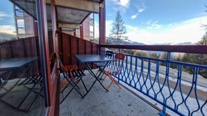 A balcony with a table and chairs, a blue railing, and a view of a snowy landscape with trees and mountains. - 100m from ski slopes, 1st floor, swimming pool, balcony, tv, 31m², Les Arcs (Les Arcs)