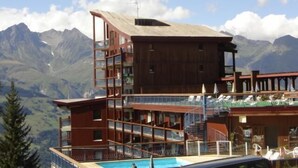 A multi-story hotel with a pool, surrounded by mountains. - 100m from ski slopes, 1st floor, swimming pool, balcony, tv, 31m², Les Arcs (Les Arcs)