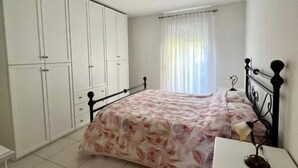 A bedroom with a bed, a nightstand, a wardrobe, and a window with curtains. - 2 bedroom apartment in lower morbio (Morbio Inferiore)