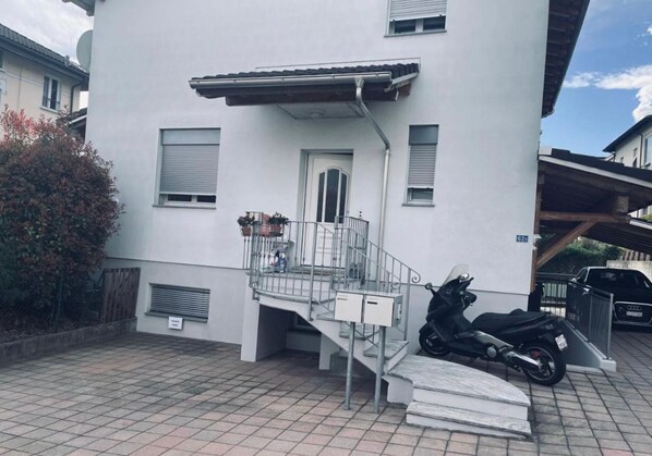 A modern two-story building with a metal staircase leading to a small balcony.