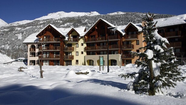 A multi-story lodge with balconies and a snowy mountain backdrop. - 100m from resort center, Ground floor, terrace, tv, ski locker, 42m², Serre Chevalier (La Salle-les-Alpes)