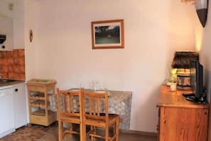Una cocina compacta con comedor, una mesa de madera con sillas, un mueble pequeño y un cuadro en la pared.