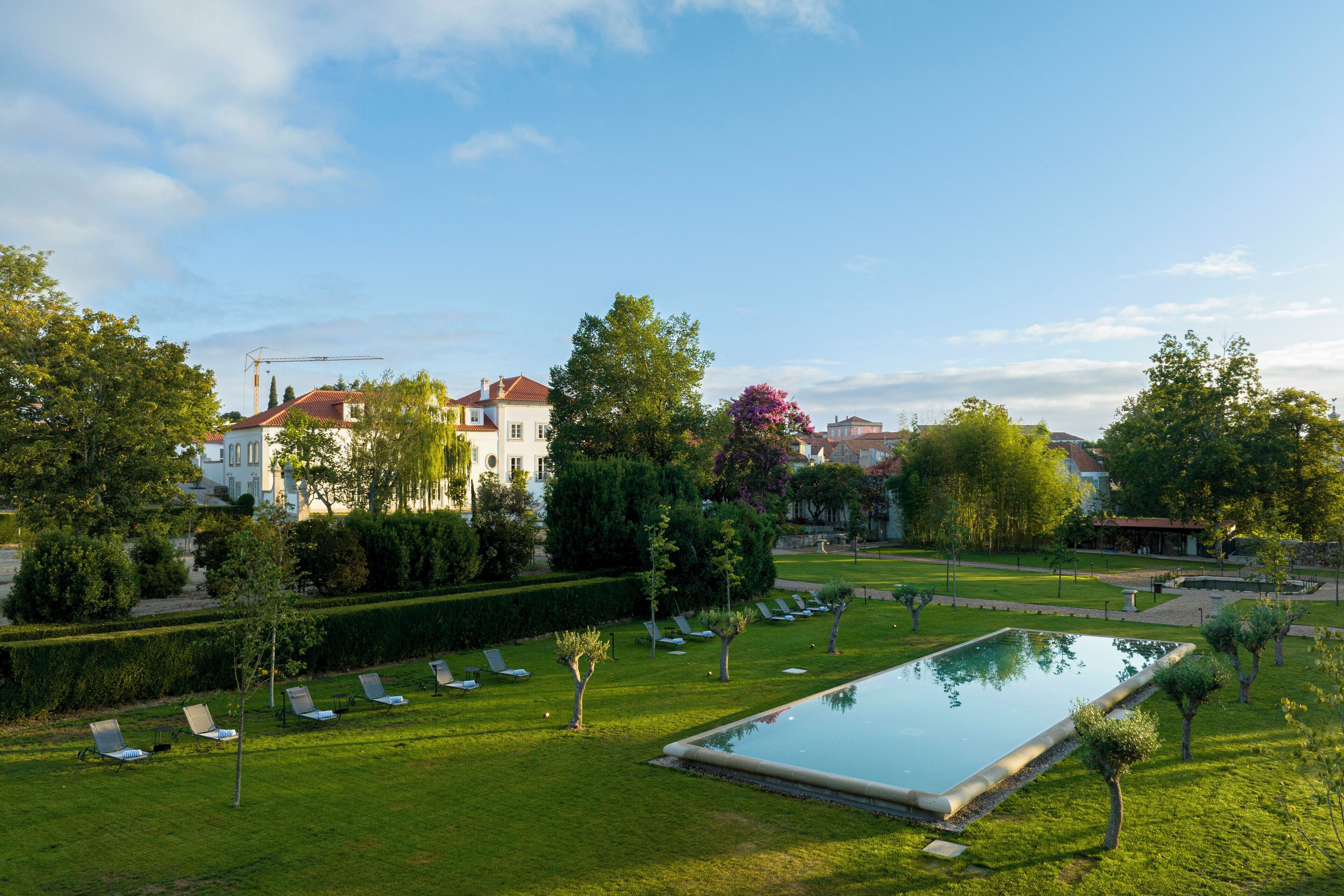 Ein Poolbereich mit Liegestühlen, einem gepflegten Rasen und einem großen Gebäude im Hintergrund.