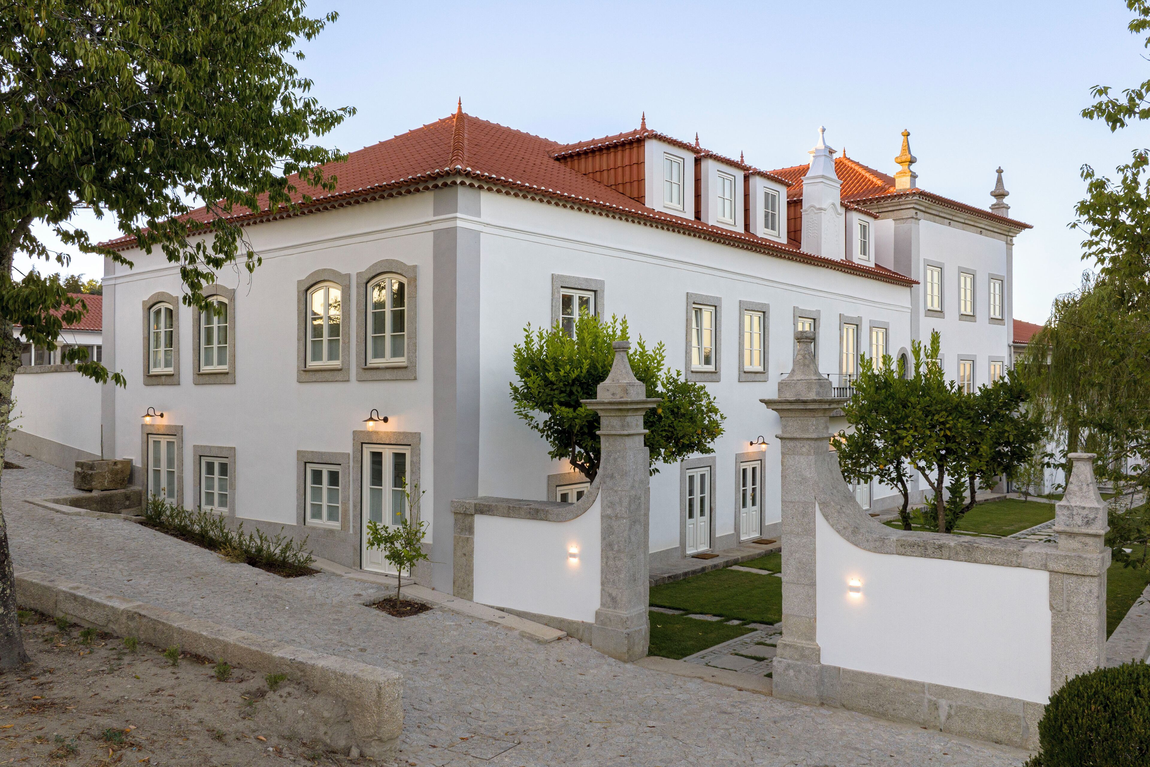 Un grand bâtiment blanc, doté d’un toit recouvert de tuiles rouges et de nombreuses fenêtres.