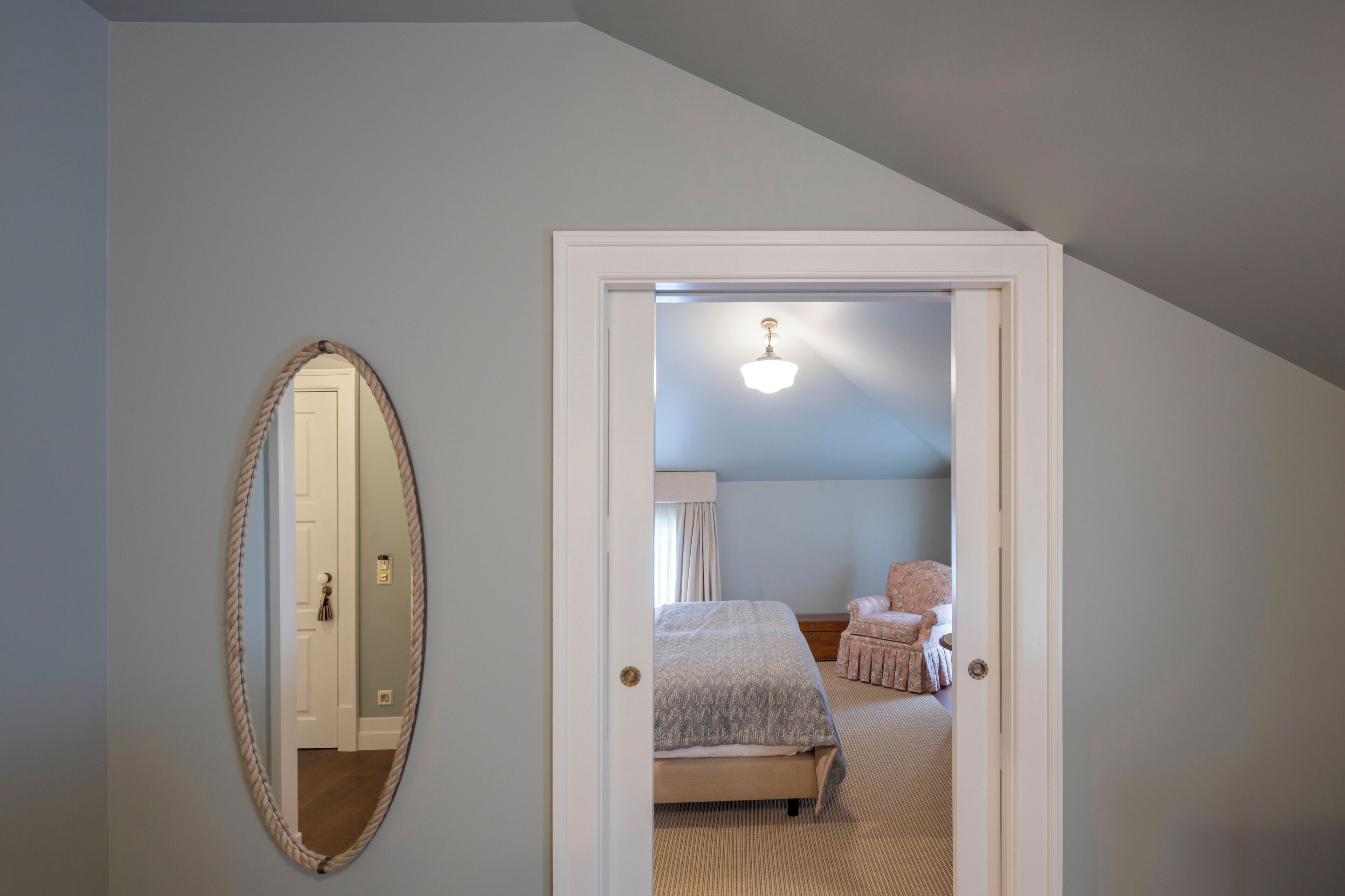 Un dormitorio con una cama, una silla y un espejo.