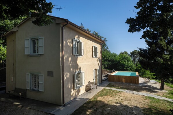 A two-story building with a pool, a wooden deck, and a bench. - Casa Sul Serra (Calci)