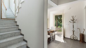 A staircase leading to a dining area with a table set for two, a coat rack, and a view of the outdoors. - Casa Sul Serra (Calci)
