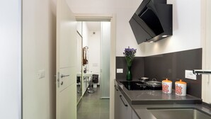 A modern kitchen with a stainless steel sink, a black range hood, and two orange and white containers on the countertop. - Casa Sul Serra (Calci)