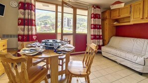 Un coin repas avec une table en bois dressée pour quatre personnes, un canapé blanc et des meubles de rangement en bois.