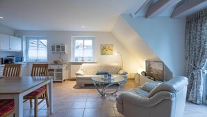 A modern living room with a dining area, a sofa, a coffee table, and a kitchen in the background. - Ferienwohnung direkt am Deich in St.Peter-Ording (St. Peter-Ording)