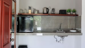 A compact kitchen with a built-in refrigerator, a sink, and a small trash bin. - Apartamento 22 (Bacalar)