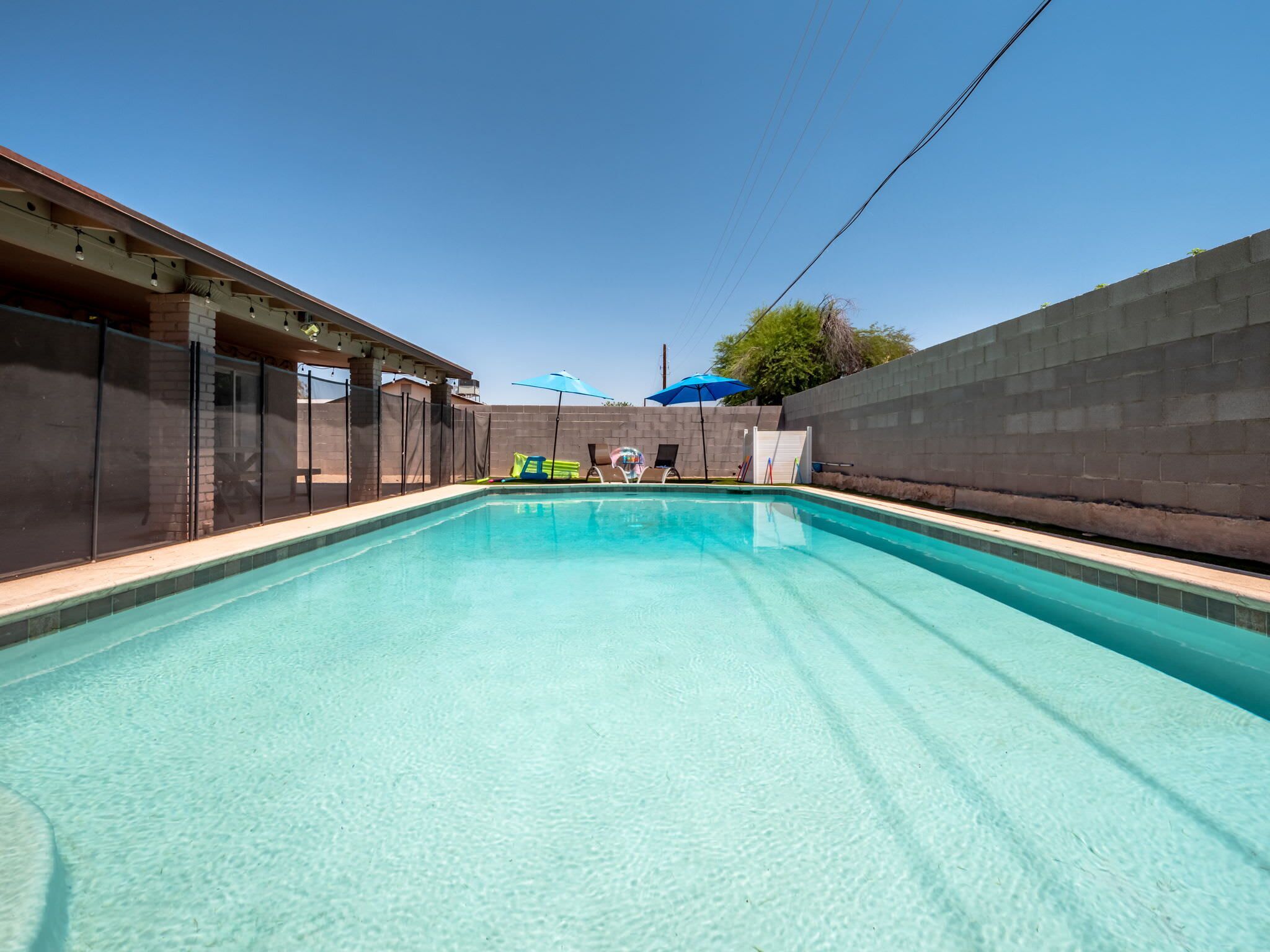 Une piscine à eau claire, avec vue sur le ciel et un mur de briques sur un de ses côtés.