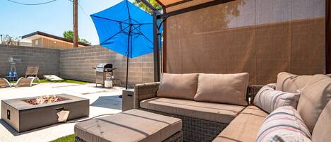 Une terrasse extérieure dotée d’un espace salon couvert, d’un barbecue et d’un foyer.