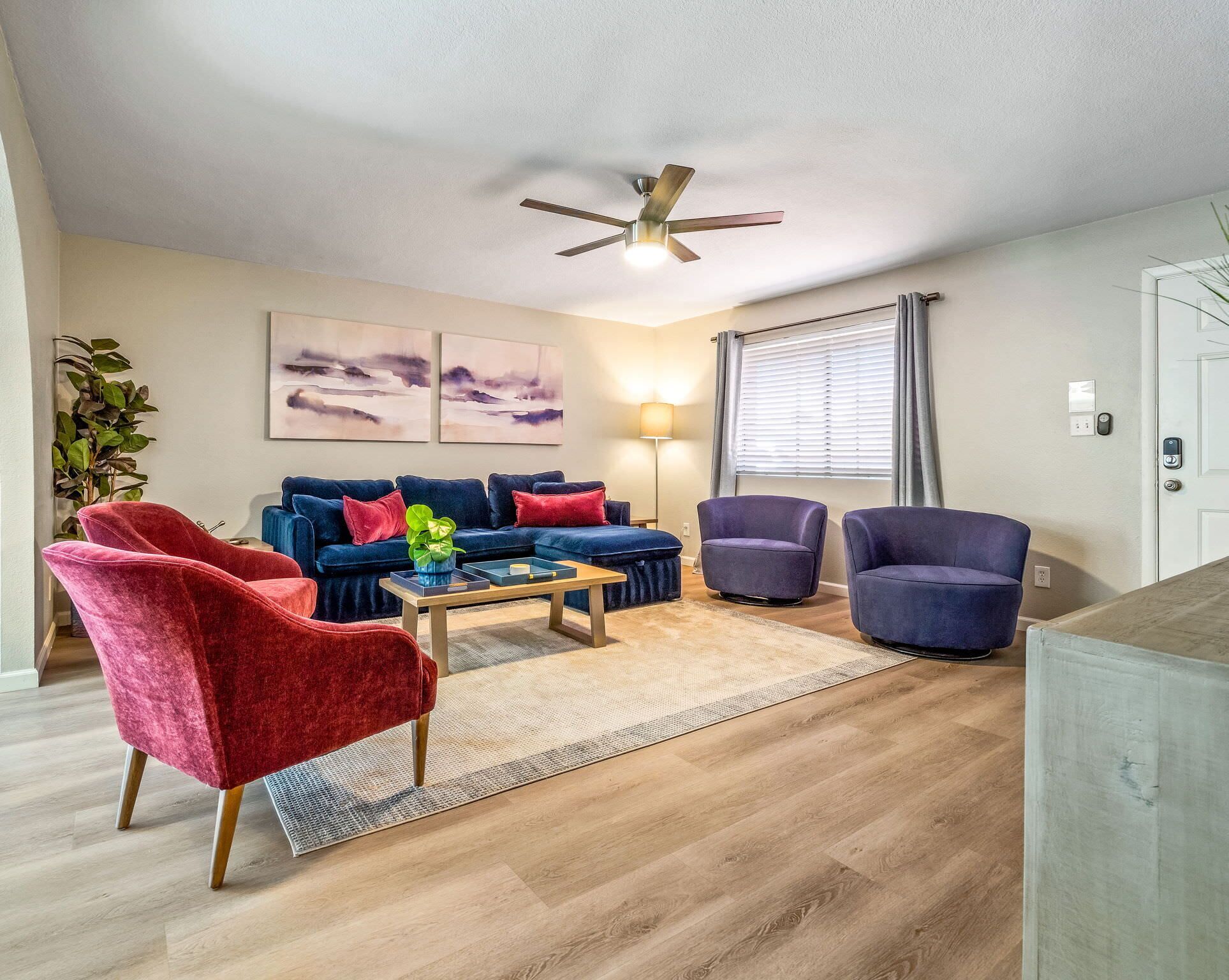 A modern living room with a sectional sofa, two armchairs, a coffee table, and a ceiling fan.