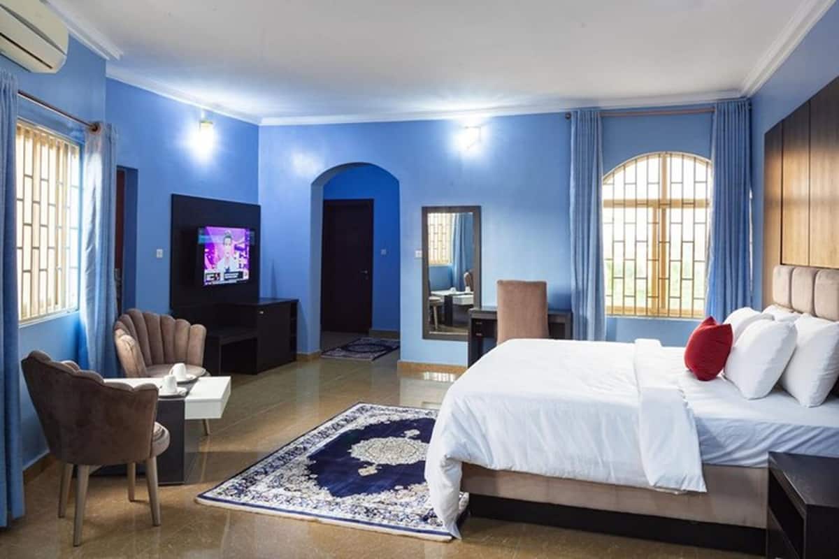 Een hotelkamer met een bed, een televisie, een bureau, een stoel en een groot raam.