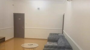 A room with a sofa, a small round table, and a door. - Royale Crown Villa Apartment (Abuja)