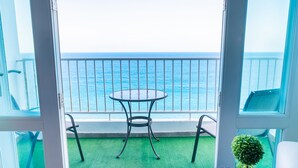 Ein Balkon mit Tisch und Stühlen, einem kleinen Topfpflanzen und Blick auf das Meer.
