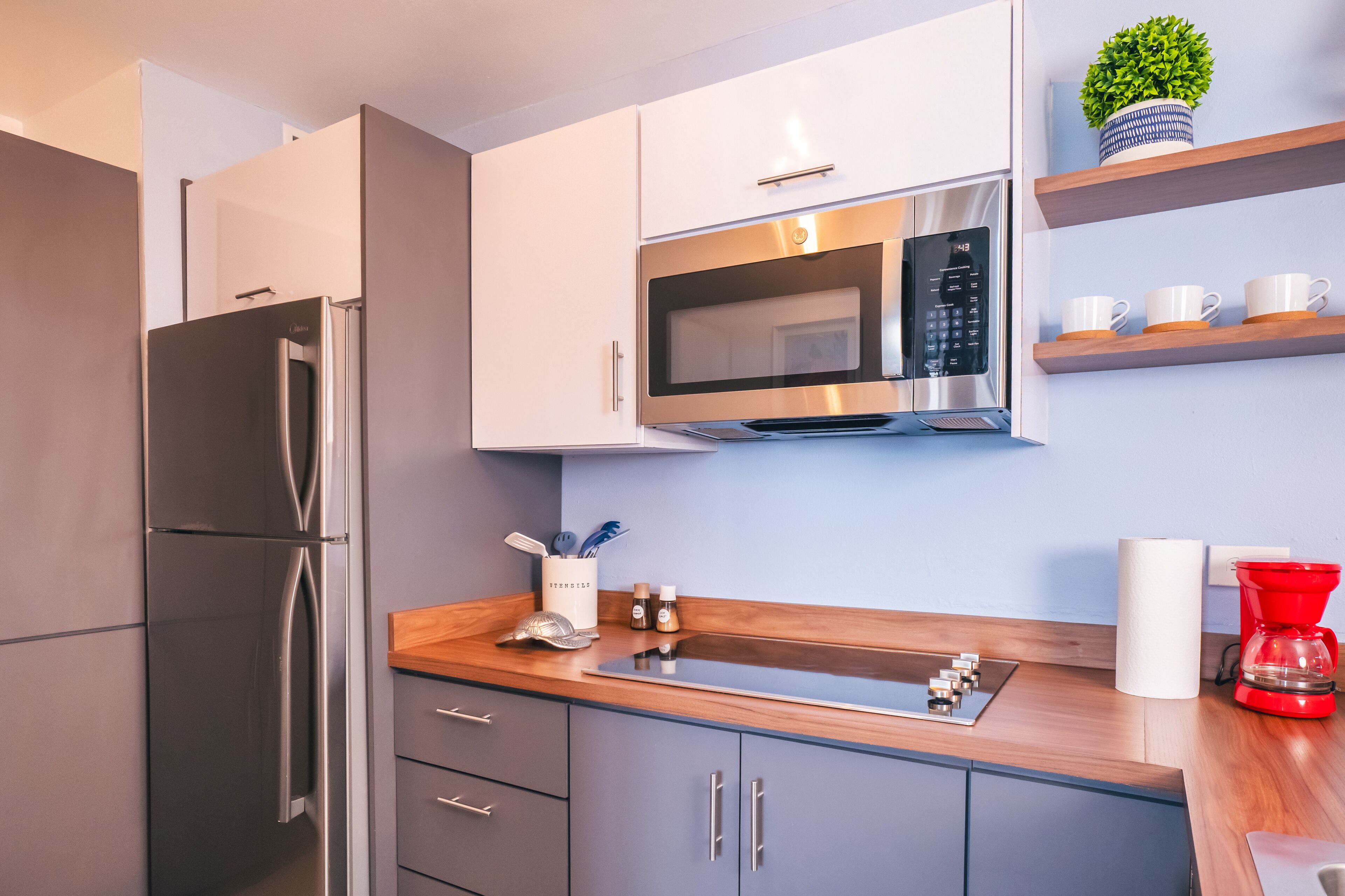 A modern kitchen with stainless steel appliances, wooden countertops, and a coffee maker.