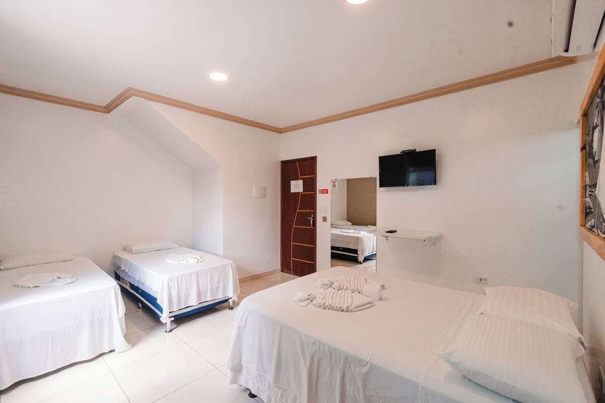 Quarto de hotel com duas camas, uma televisão, um espelho e uma porta com um aviso.