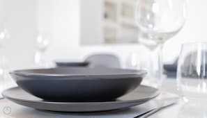 A dining table with a dark bowl and plate, a wine glass, and a fork.