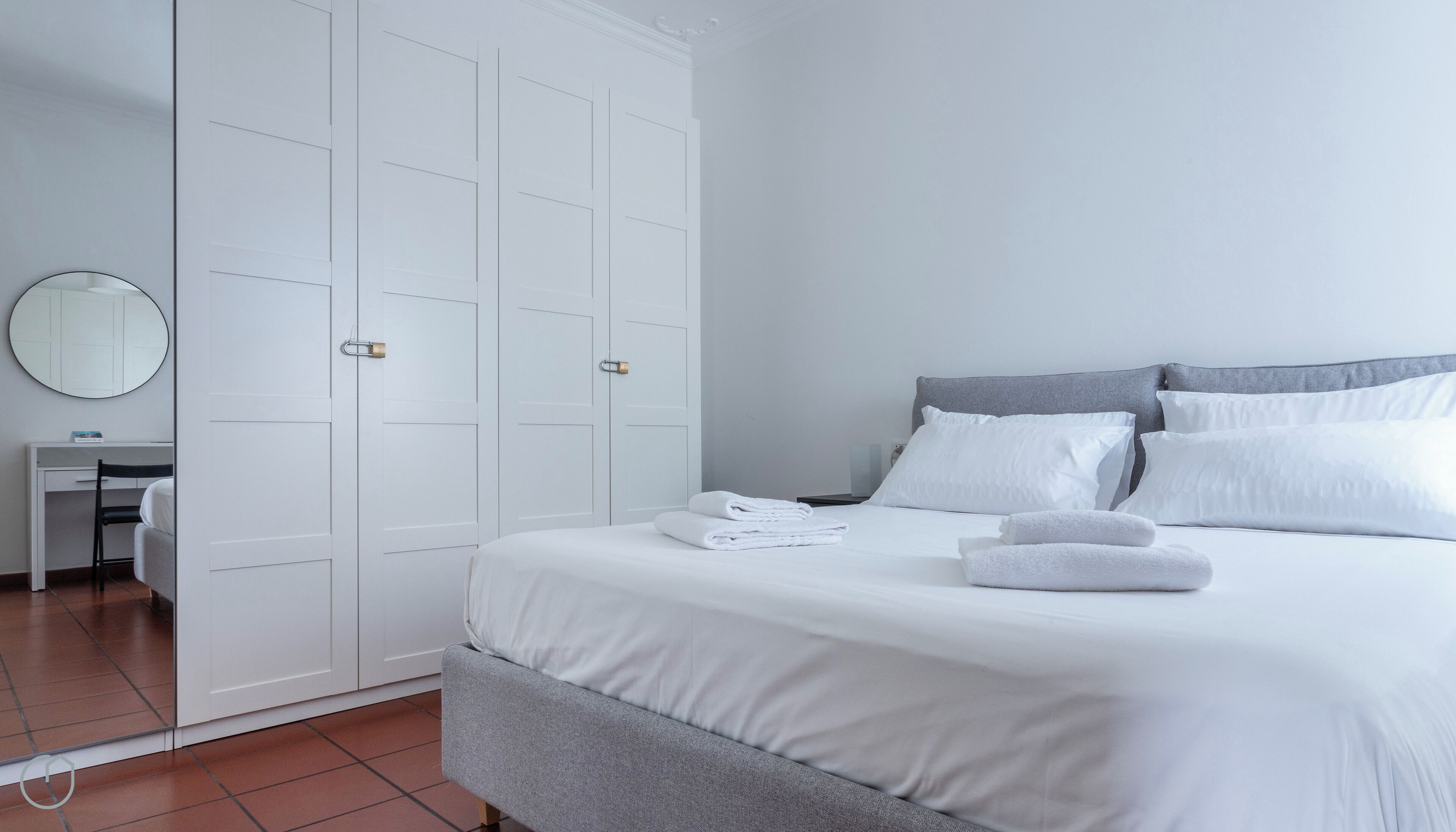 A bedroom with a bed, a desk, and a wardrobe.