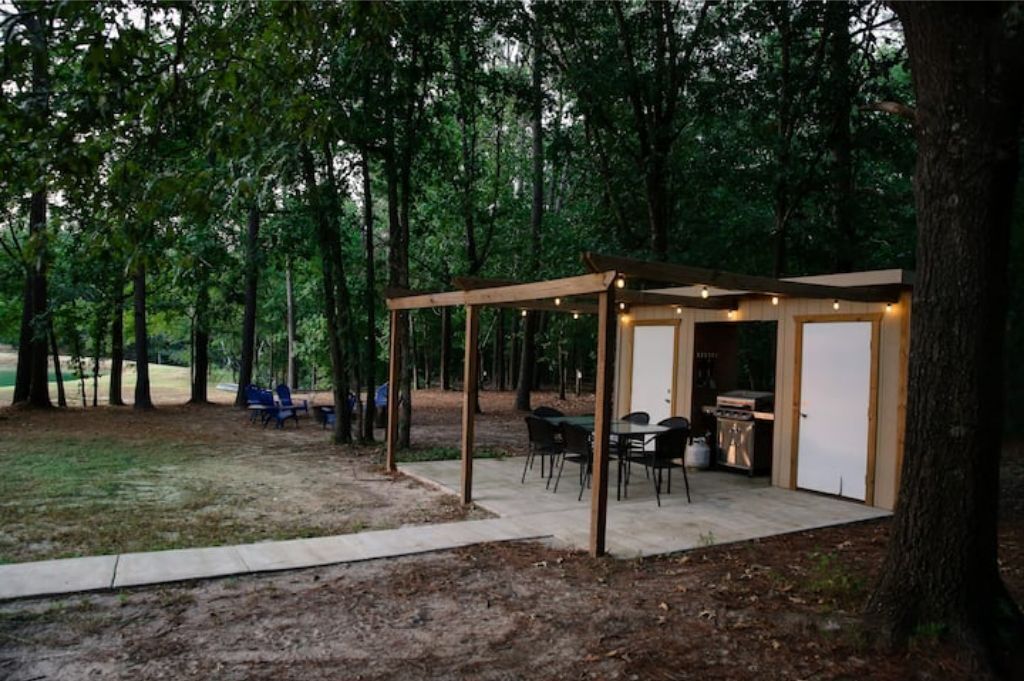 Un espace extérieur abrité, doté d’une table et de chaises, et entouré d’arbres.