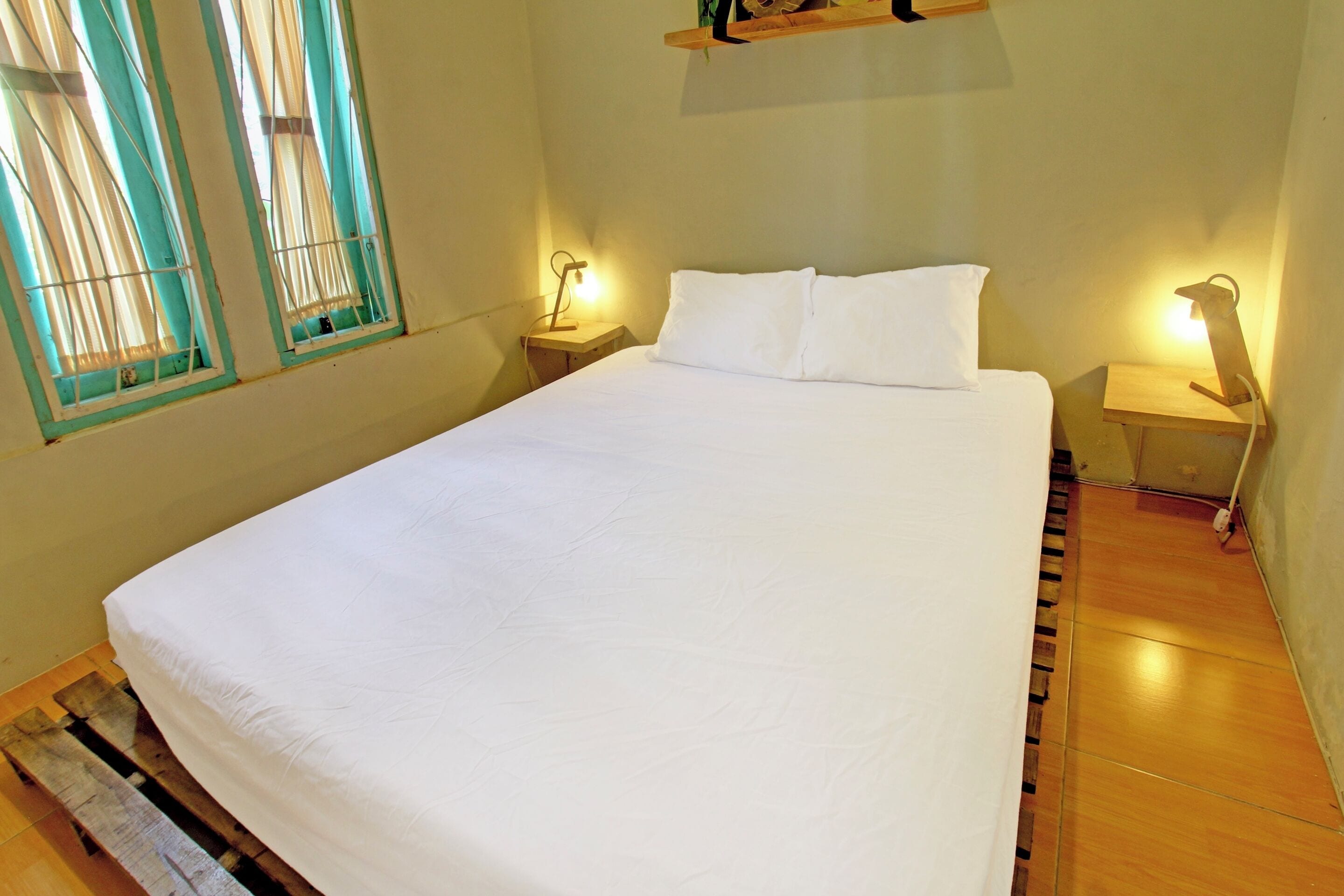 A neatly made bed with white bedding, wooden headboard, and two bedside tables with lamps.