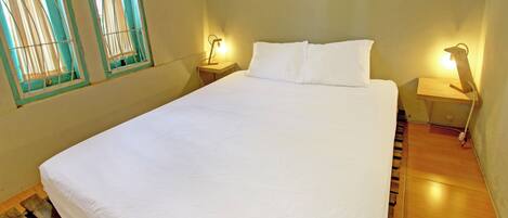 A neatly made bed with white bedding, wooden headboard, and two bedside tables with lamps.