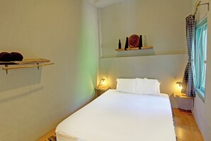 Comfortable retreat with a neatly made bed, bedside tables, and a convenient shelf above.