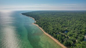 Luchtbeeld van een kustbosgebied met een strand en weelderige begroeiing.