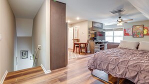 A bedroom with a bed, a desk, and a chair. There is a staircase leading to another room. - Cozy Covington Studio Rental Near Historic Square! (Covington)