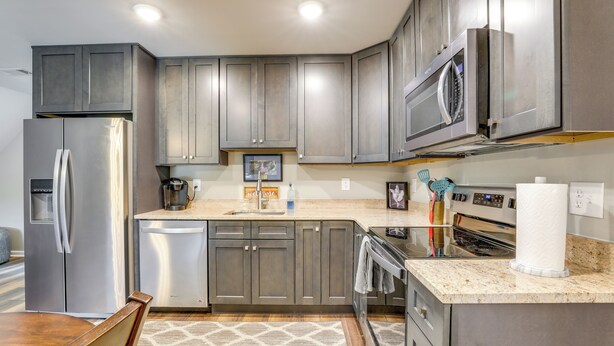 A modern kitchen with stainless steel appliances, grey cabinetry, and a granite countertop. - Cozy Covington Studio Rental Near Historic Square! (Covington)