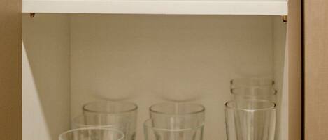 A shelf with two wine glasses and four water glasses.