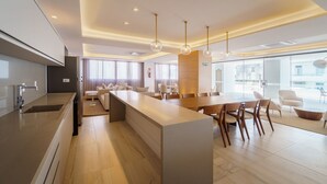 Een moderne keuken met een centraal eiland, een zithoek met houten stoelen, en een groot raam dat natuurlijk licht binnenlaat.