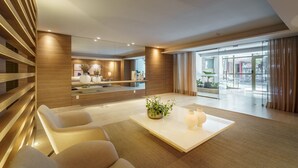 Een moderne woonkamer met een bank, een salontafel en een groot raam met gordijnen.
