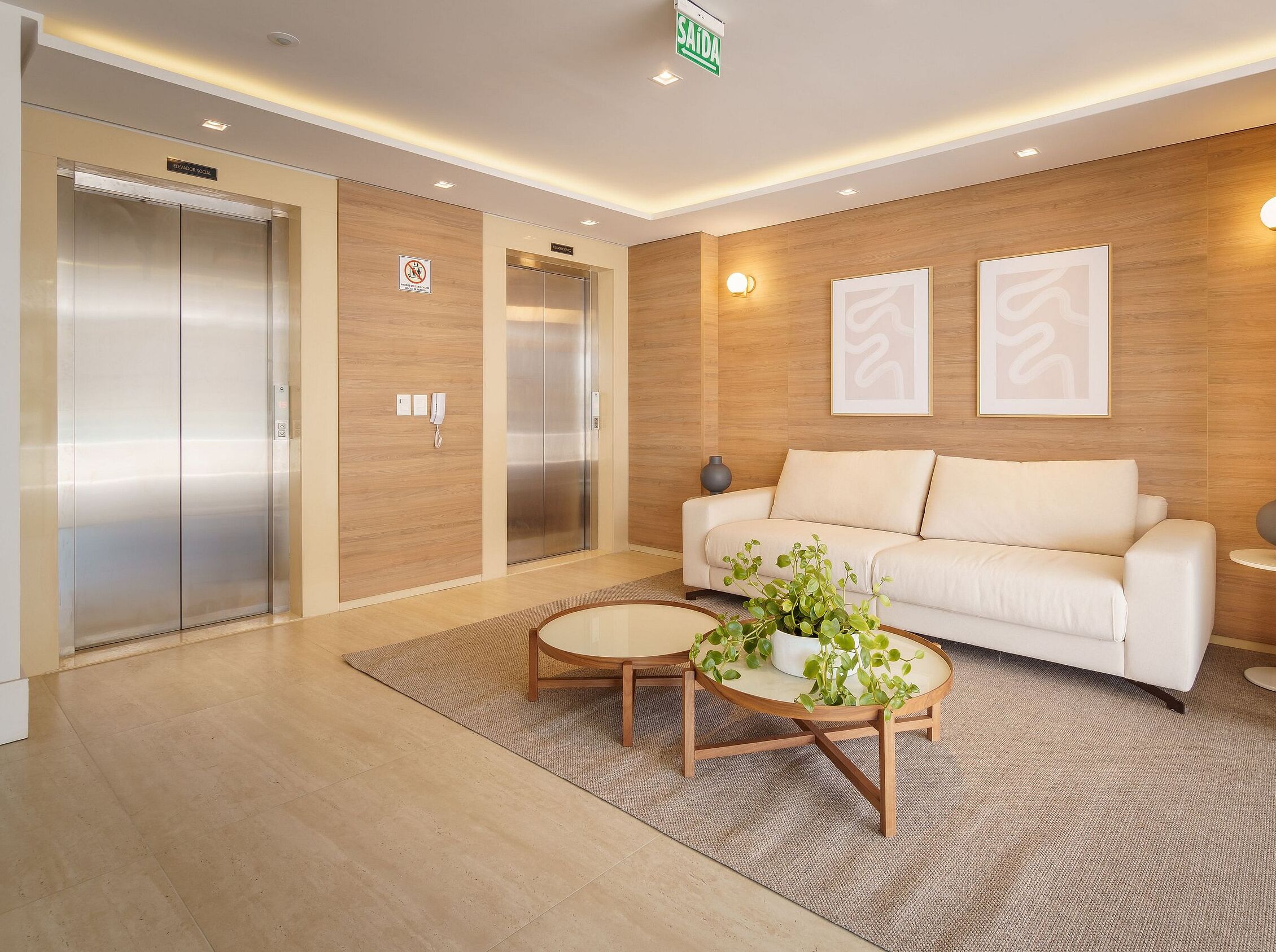 Um lobby moderno com dois elevadores, um sofá, uma mesa de centro e um vaso de plantas.