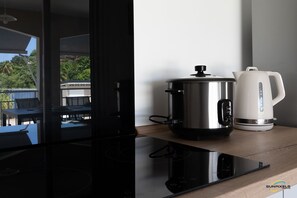 Une cuisine moderne équipée d’une mijoteuse en acier inoxydable et d’une bouilloire électrique blanche, le tout posé sur un plan de travail en bois.