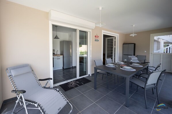 A modern outdoor dining area with a table set for four, surrounded by chairs.