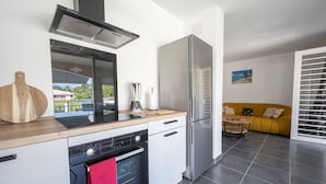 A modern kitchen with a built-in oven, a stainless steel refrigerator, and a wooden countertop. - L'anse Plage. Situation Géographique Idéale (L'anse a l'âne)