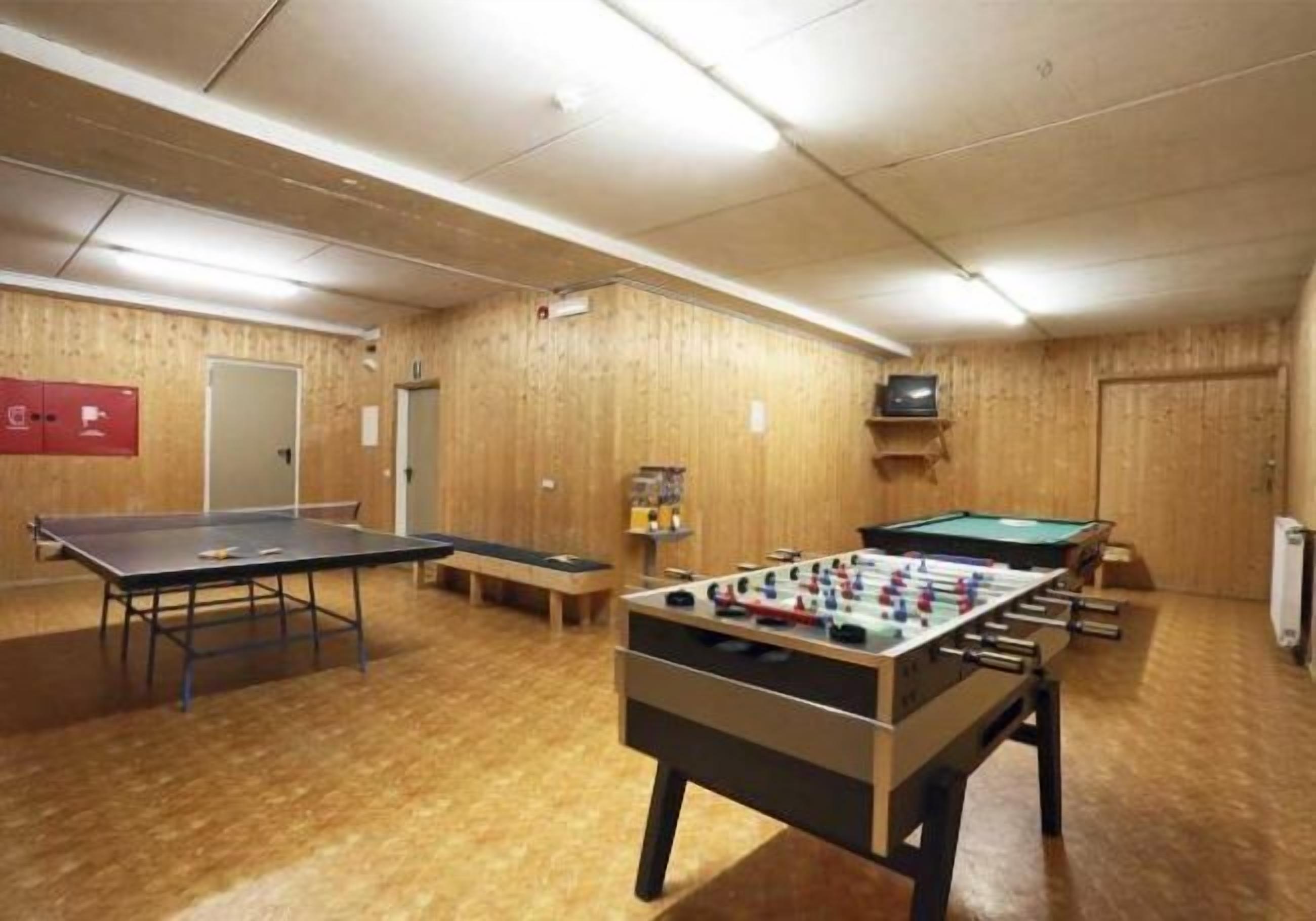 Una habitación con mesa de ping pong, mesa de fútbol y mesa de billar.