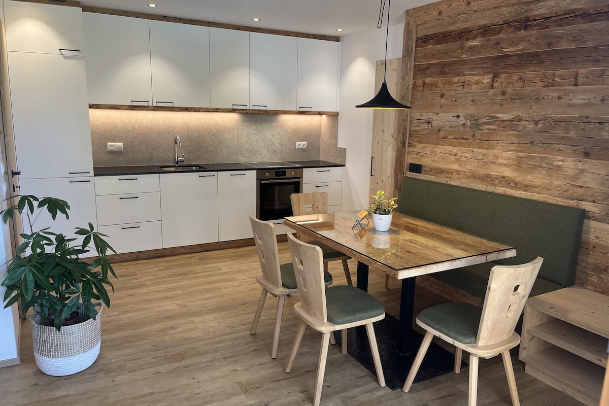 Una cocina moderna con armarios blancos, una mesa de comedor de madera y un banco.