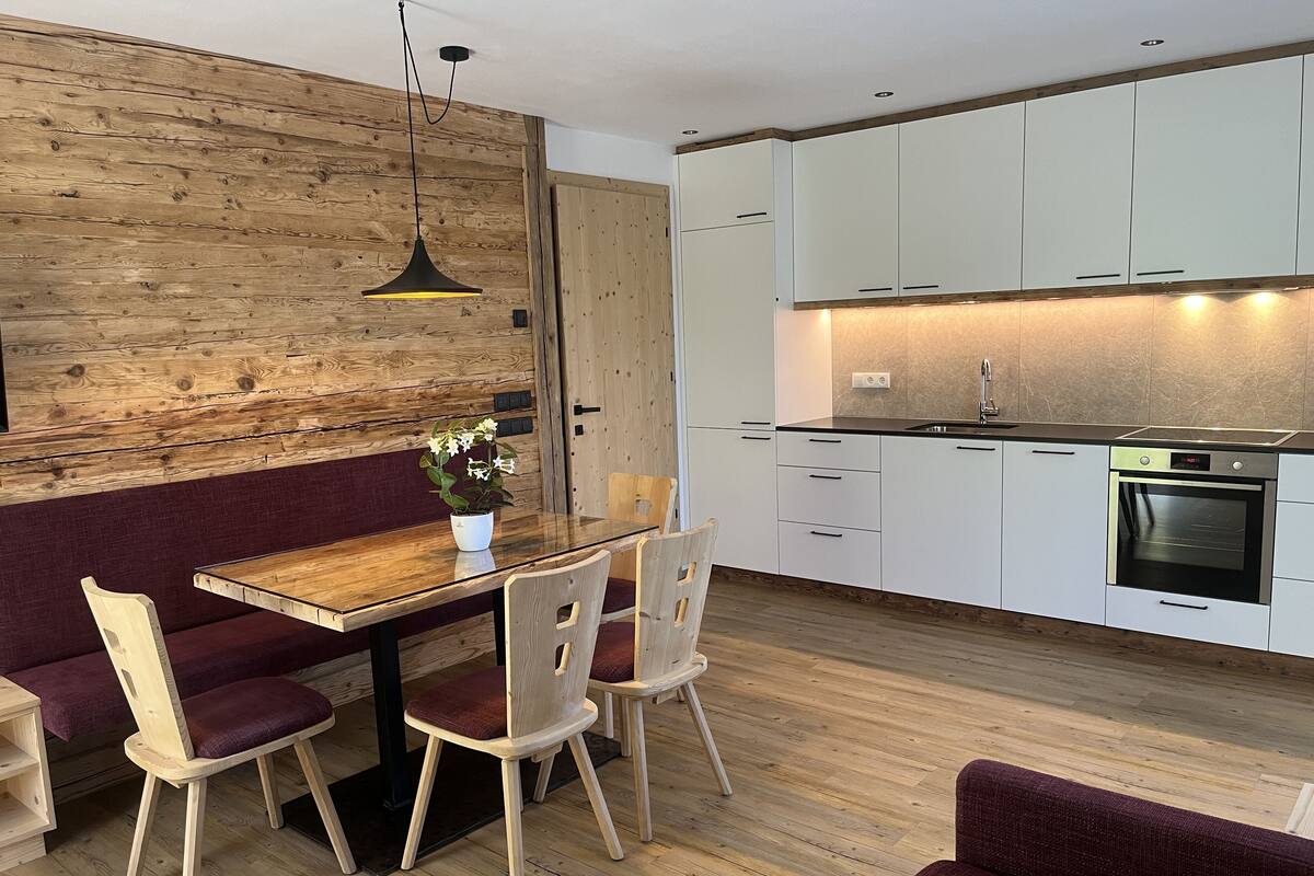 Una cocina moderna con armarios blancos, una mesa de comedor de madera y sillas.