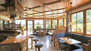 Ein Restaurant mit Barbereich, Sitzgelegenheiten und großen Fenstern mit Blick ins Freie.