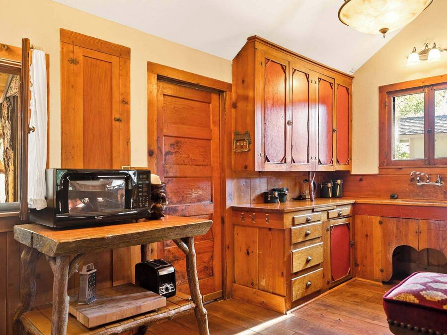 A rustic kitchen with wooden cabinets, a microwave, and a wooden table.