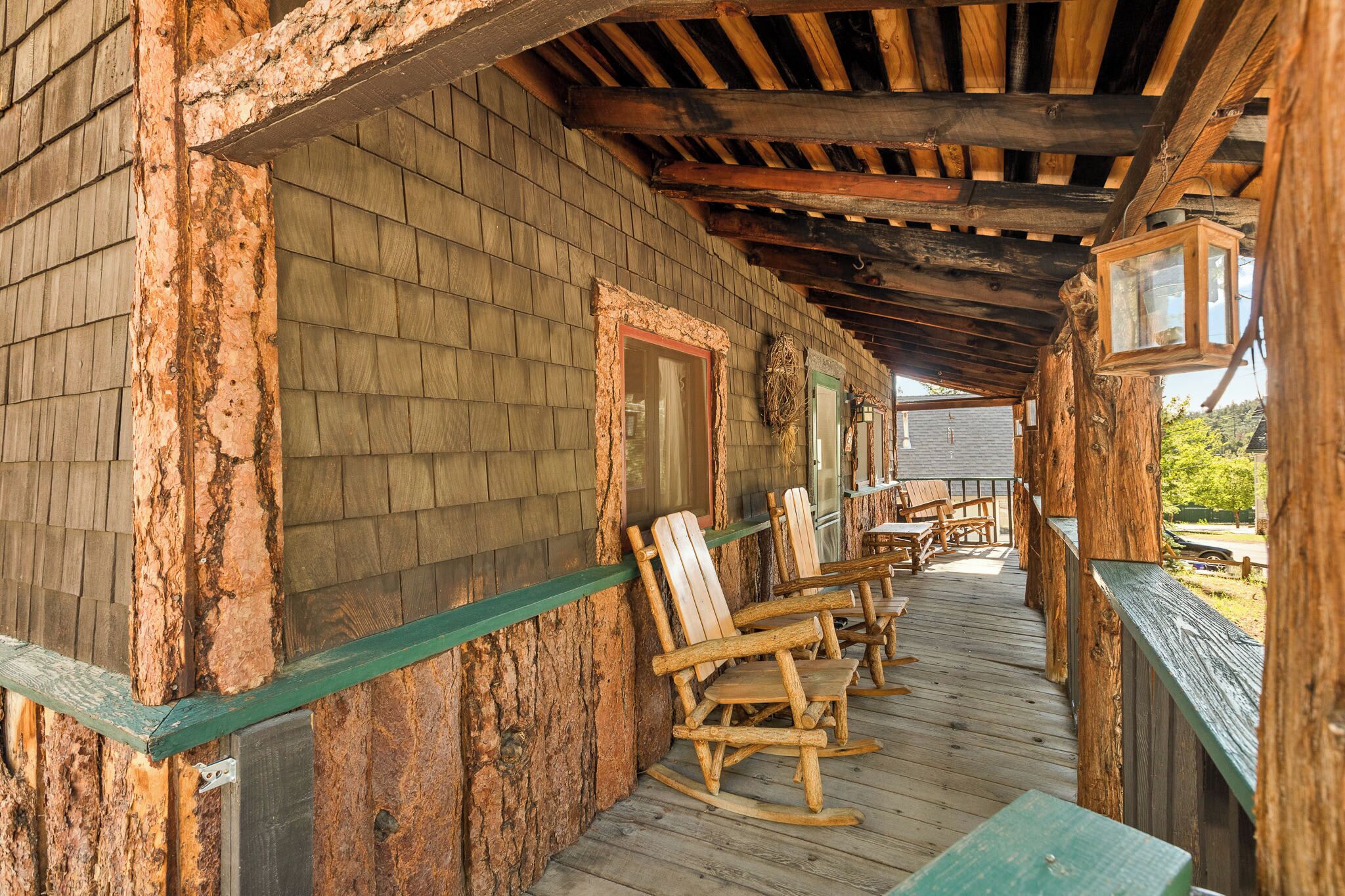 A rustic wooden porch with rocking chairs and a green railing.