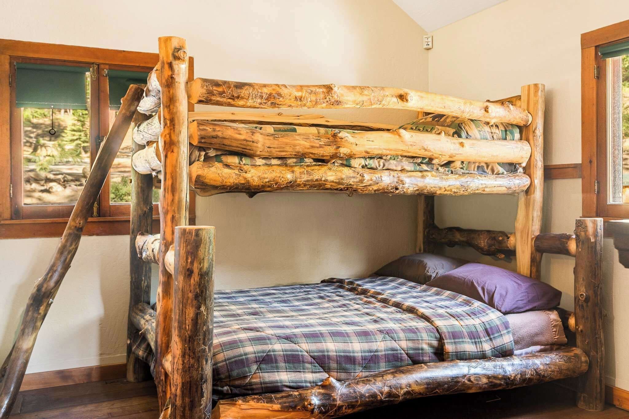 A bunk bed with a wooden frame and a plaid bedspread.