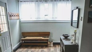 A room with a wooden floor, a bench, a sofa, a small table, and a window with curtains. - Keuka Village House, Penn Yan
 (Penn Yan)