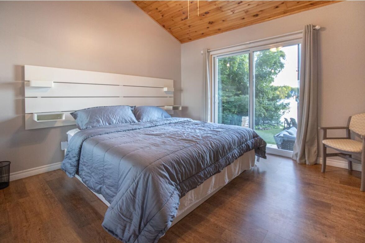 Ein Schlafzimmer mit einem großen Bett, Holzboden und einer Schiebetür zu einem Balkon.