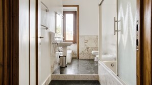 Ein schmales Badezimmer mit Waschbecken, Toilette und Dusche.